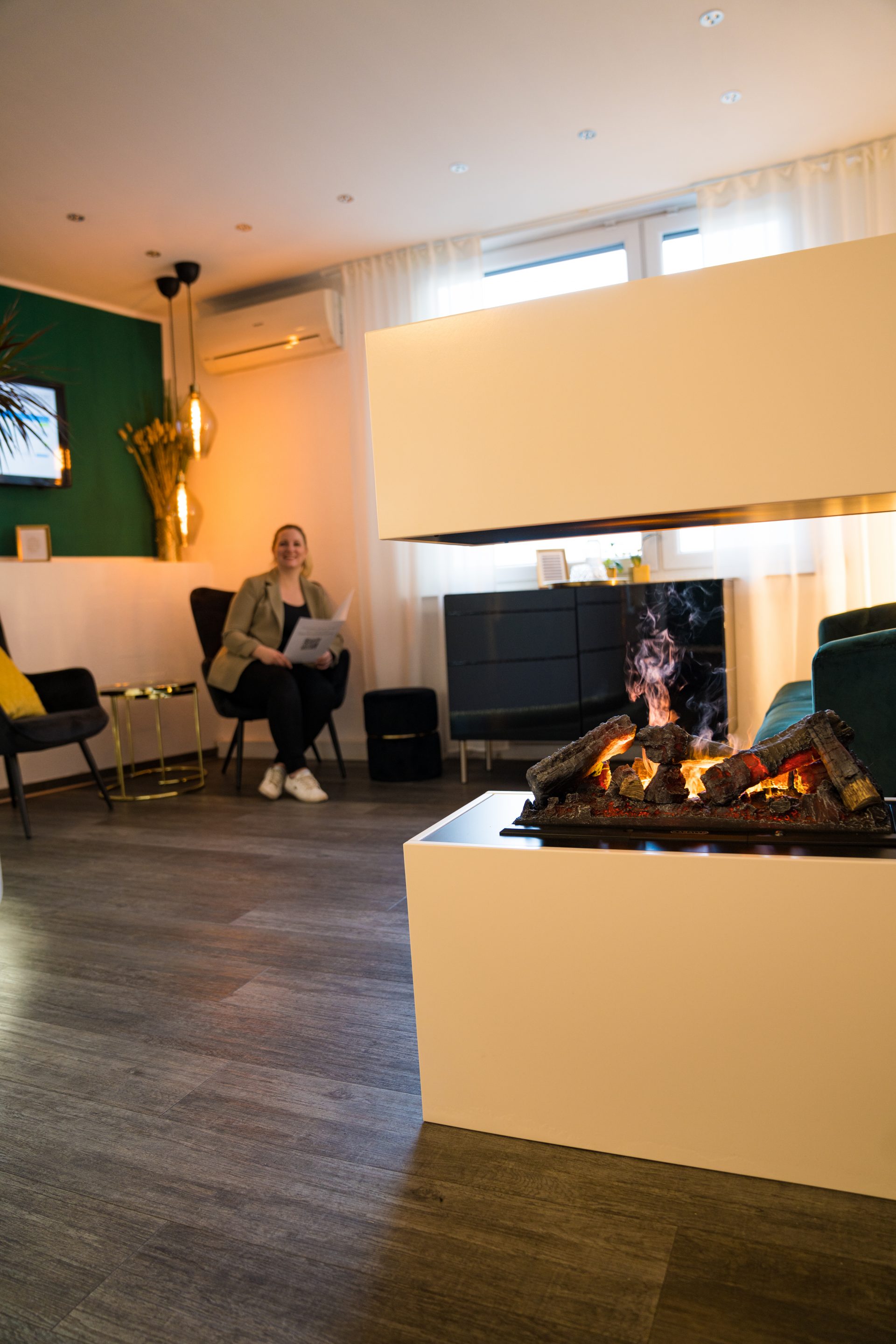 Wartebereich der Zahnarztpraxis Schoumakers in Bochum mit Kamin, Sesseln und grüner Wand